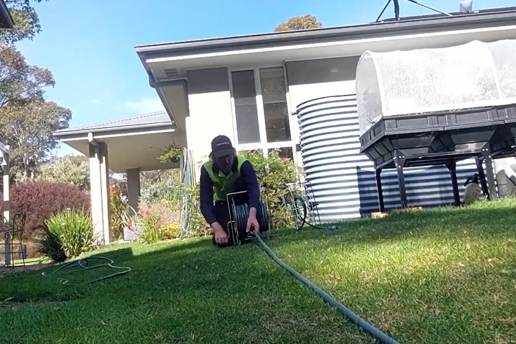 
The merimbula downpipe cleaner is finishing his day by neatly storing his hose.